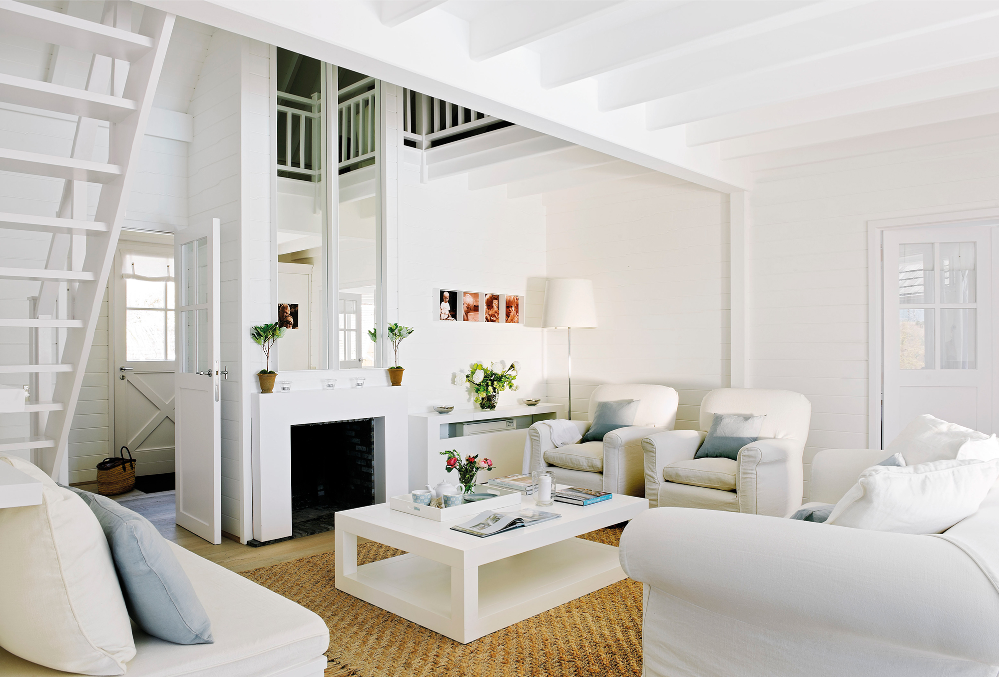 Salón en blanco con chimenea y alfombra de fibras.