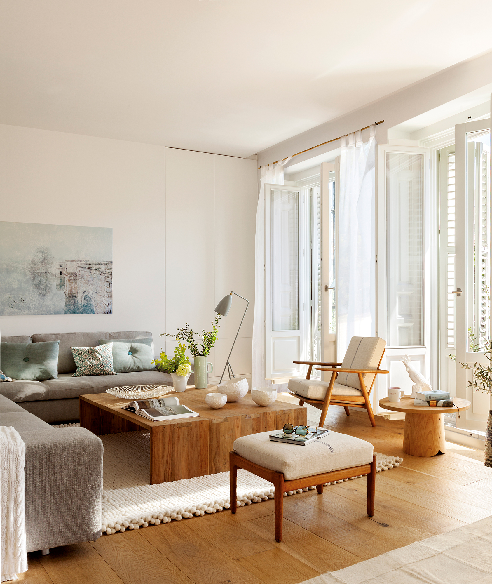 Salón con mesa de centro y auxiliar de madera  y sofá rinconero gris.
