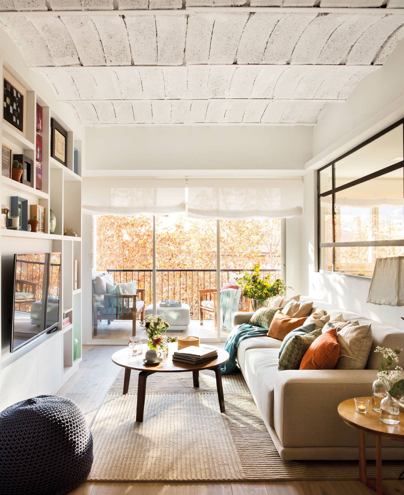 Salón con estantería de obra, sofá beige y gran ventana. 