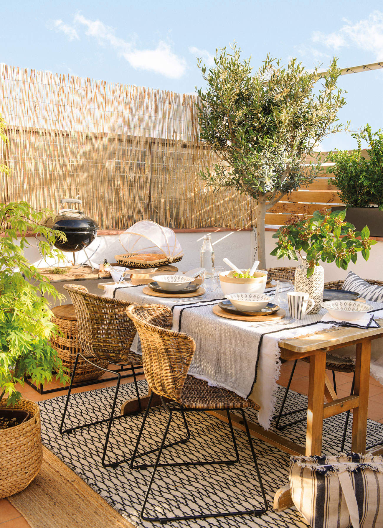 Terraza con panel de fibras vegetales y muebles de madera y ratán.