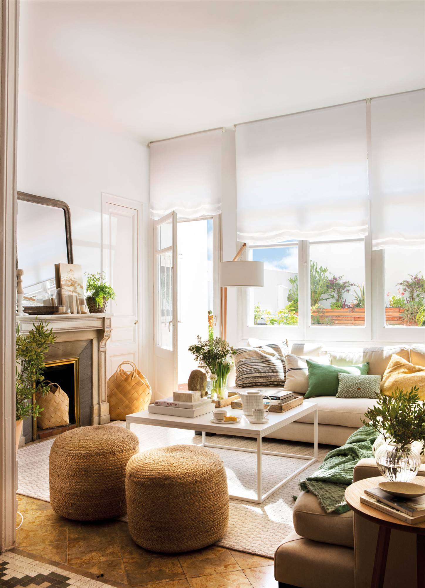 Salón pequeño con chimenea, sofás y mesa de centro blancos. 