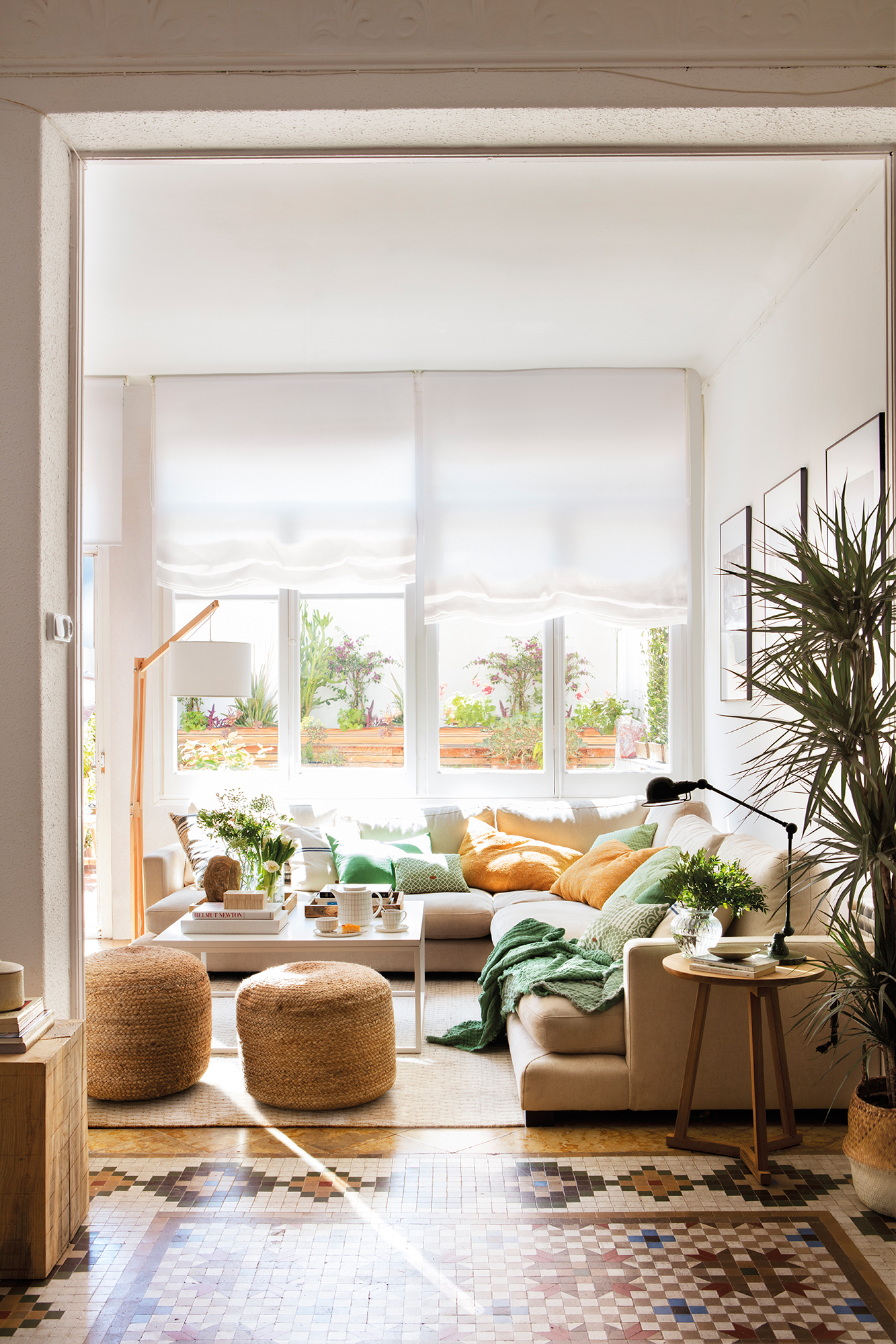 Salón moderno con sofá rinconero con chaise longue beige, puffs de fibras y estores.