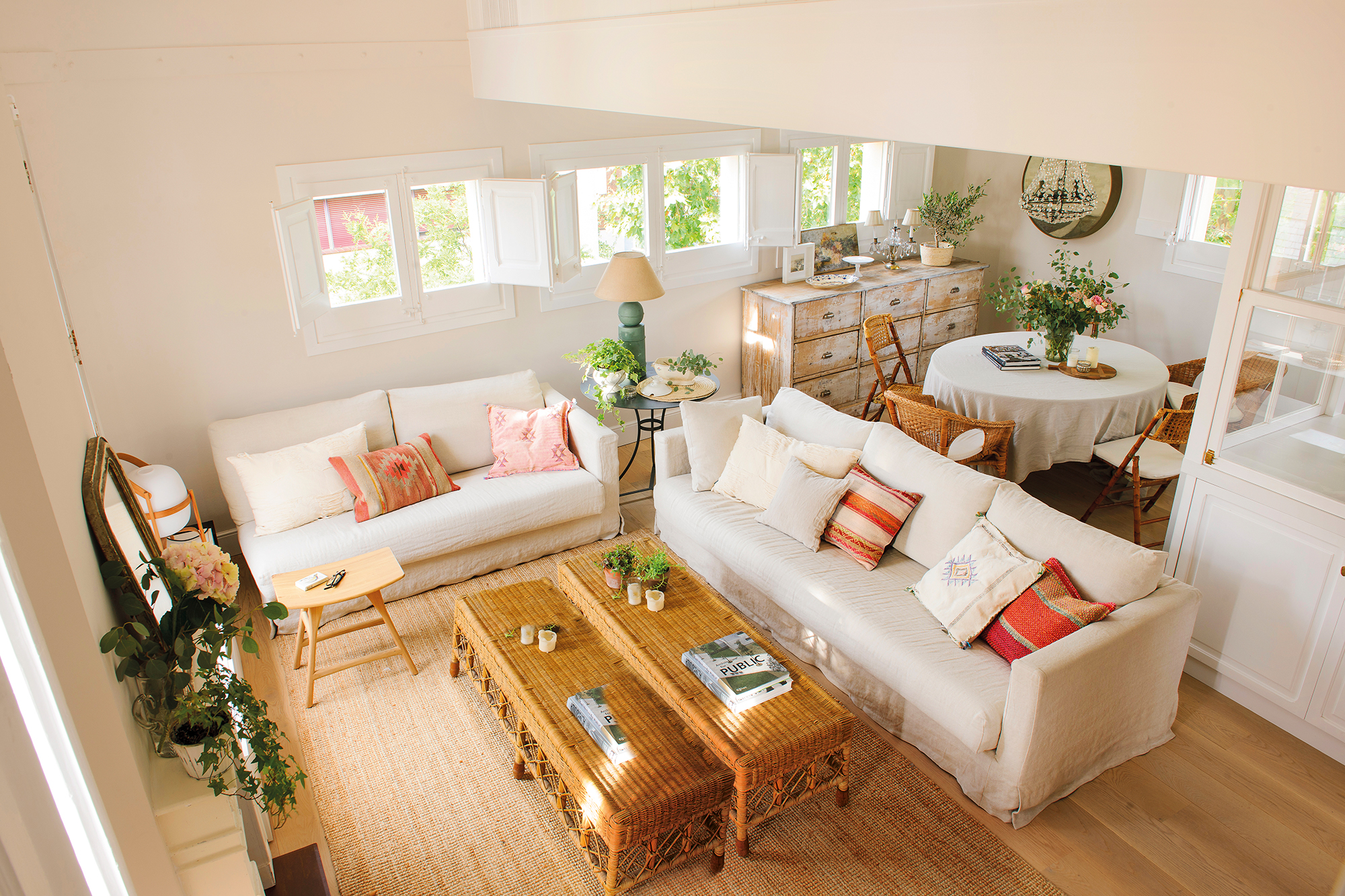 Salón moderno con aire boho con mesas de centro y alfombra, de fibras. Sofás blancos con cojines de colores.