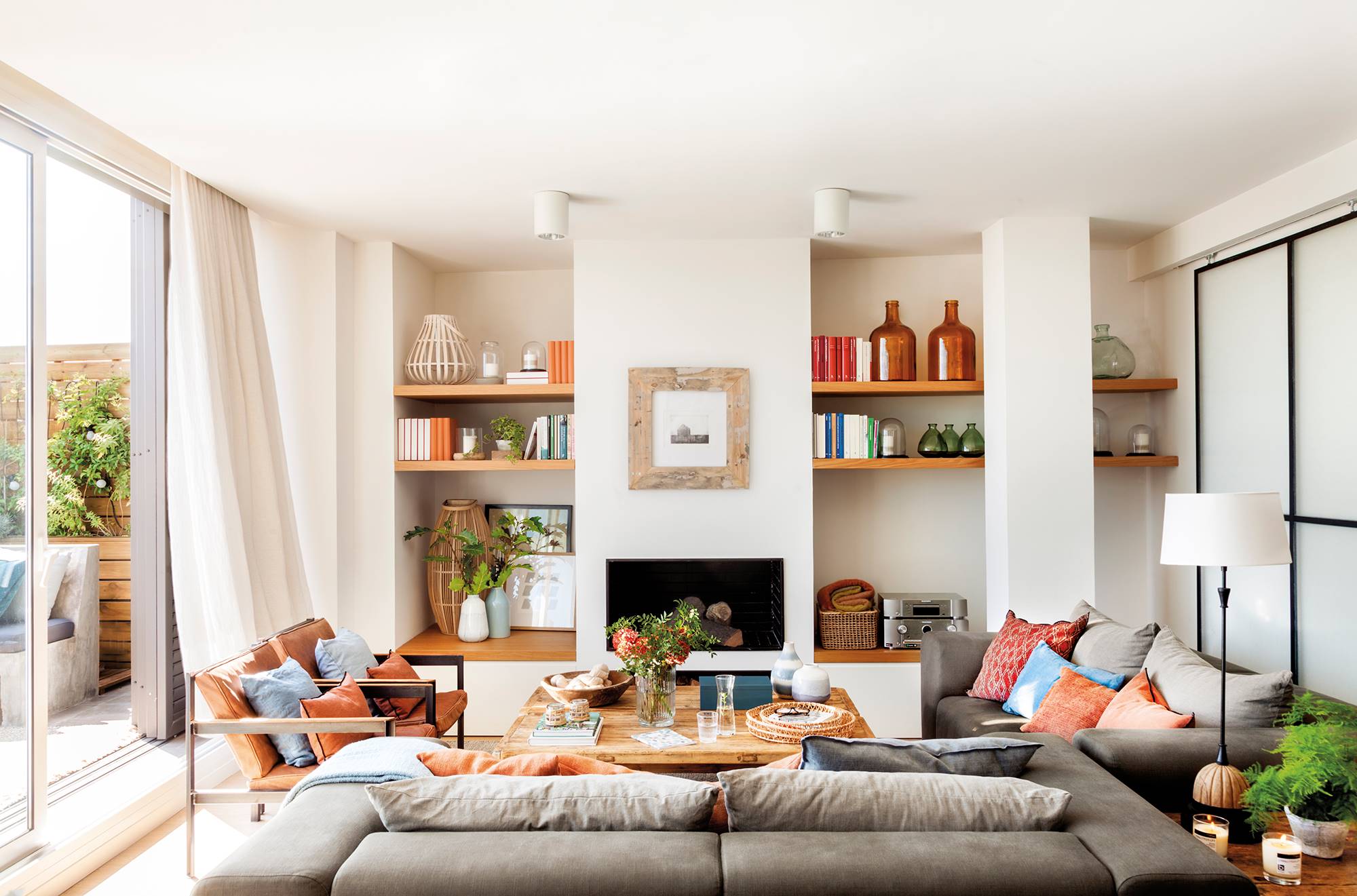 Salón pequeño con sofás grises y chimenea moderna. 