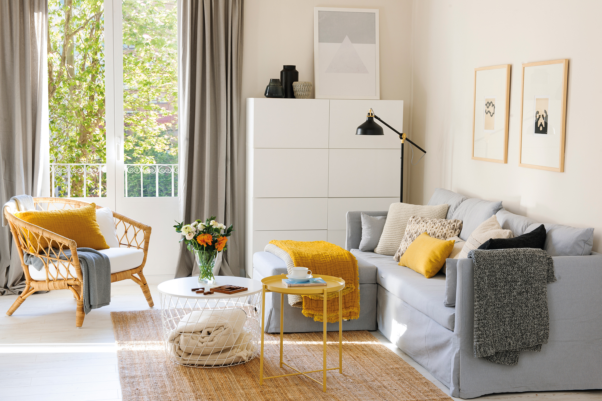 Salón moderno y pequeño con sofá gris con puff a juego y accesorios como plaids y buatca en color mostaza.