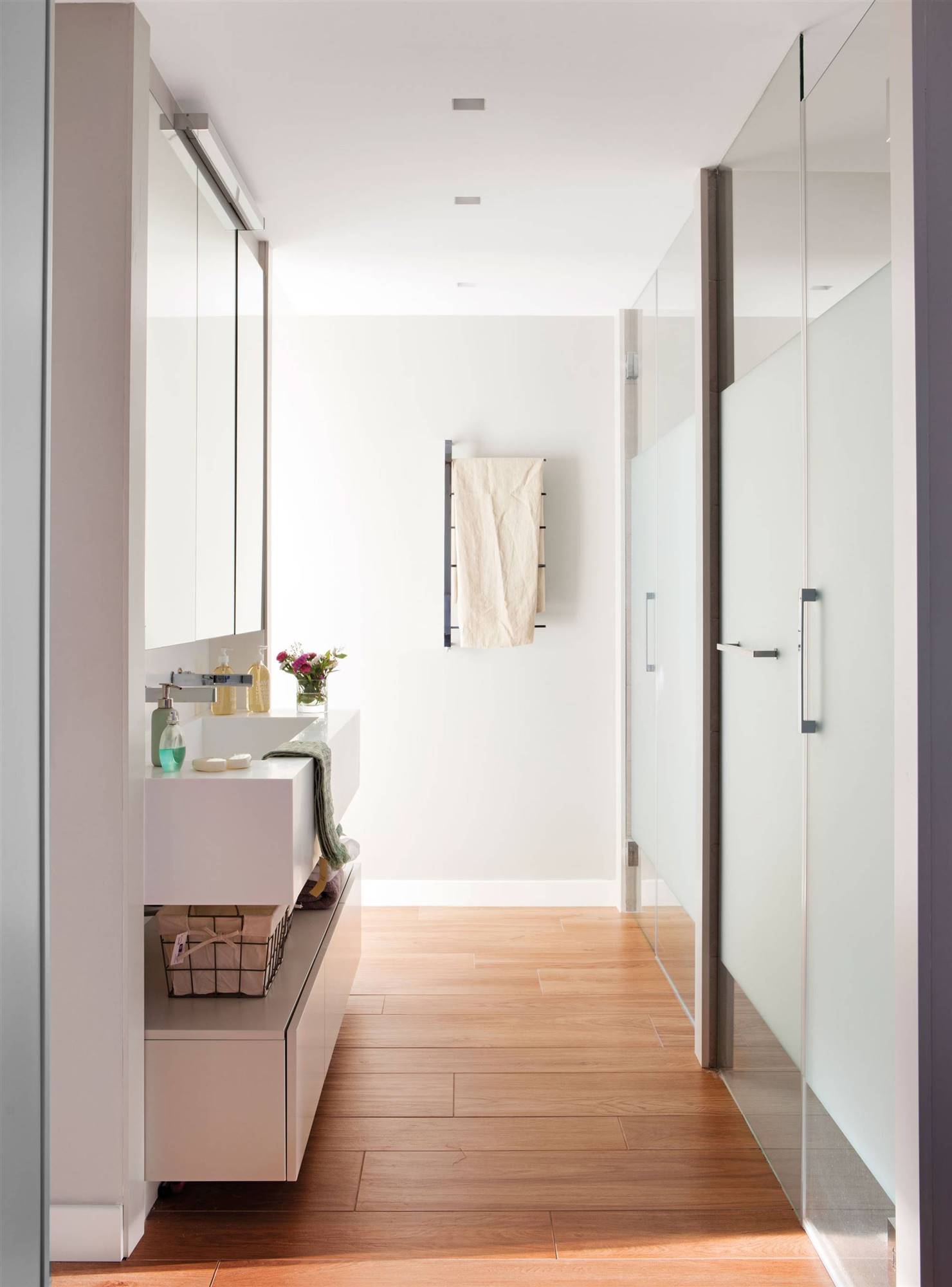 Baño moderno alargado con cabinas. 