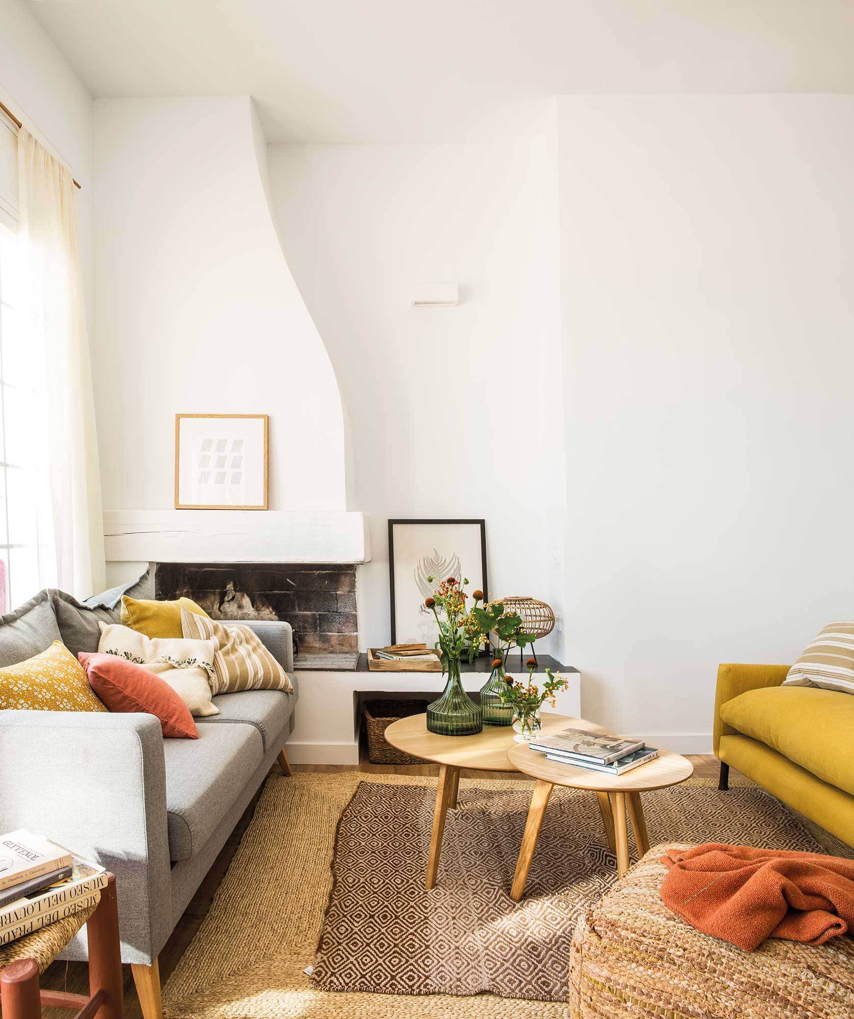 Salón blanco con chimenea y sofás gris y amarillo. 