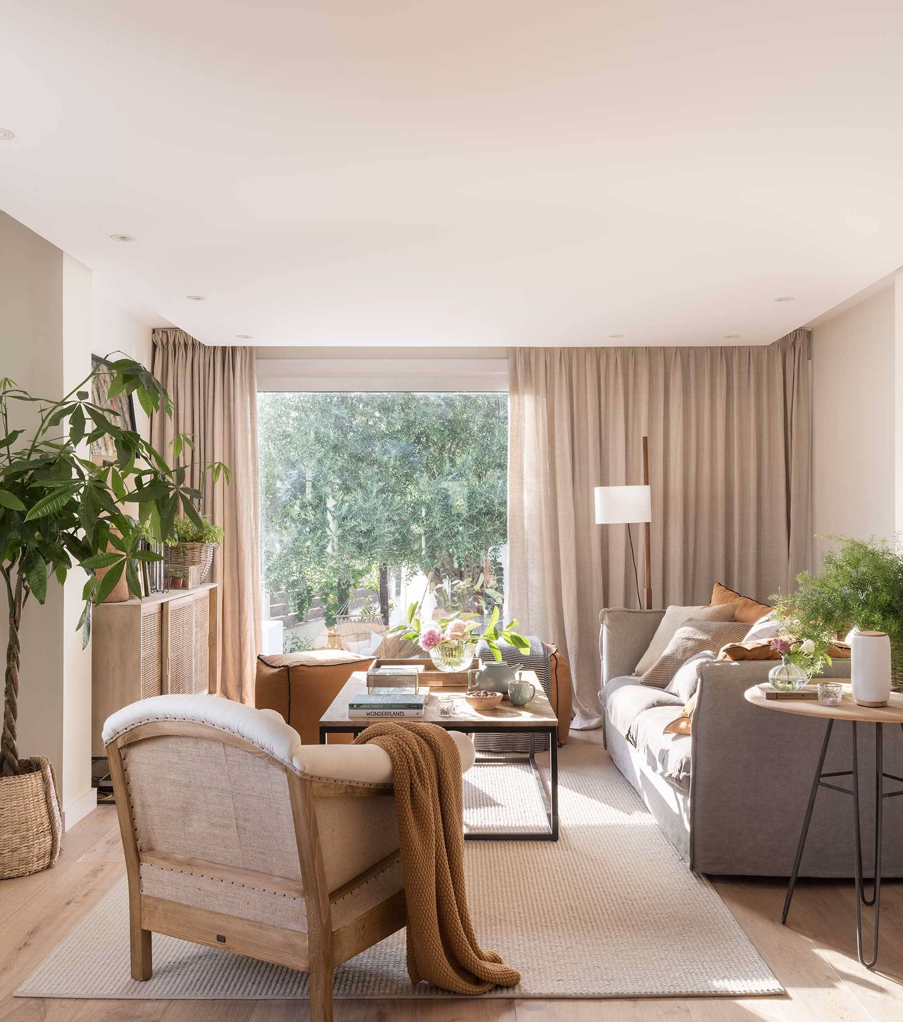 Salón pequeño con sofá y cortinas en tonos neutros y mesa de centro de madera. 