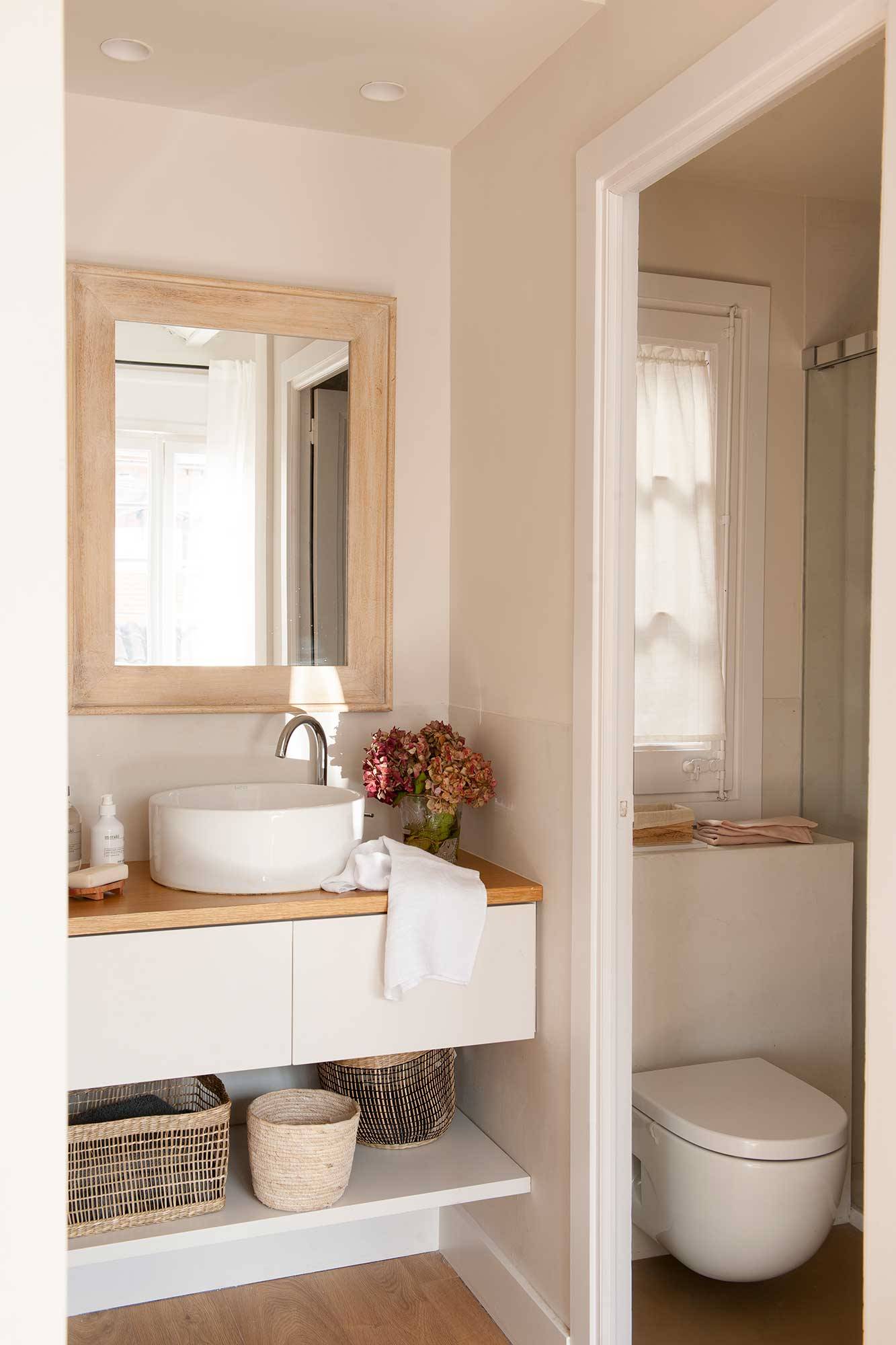 Baño con mueble en blanco suspendido e inodoro en la cabina. 