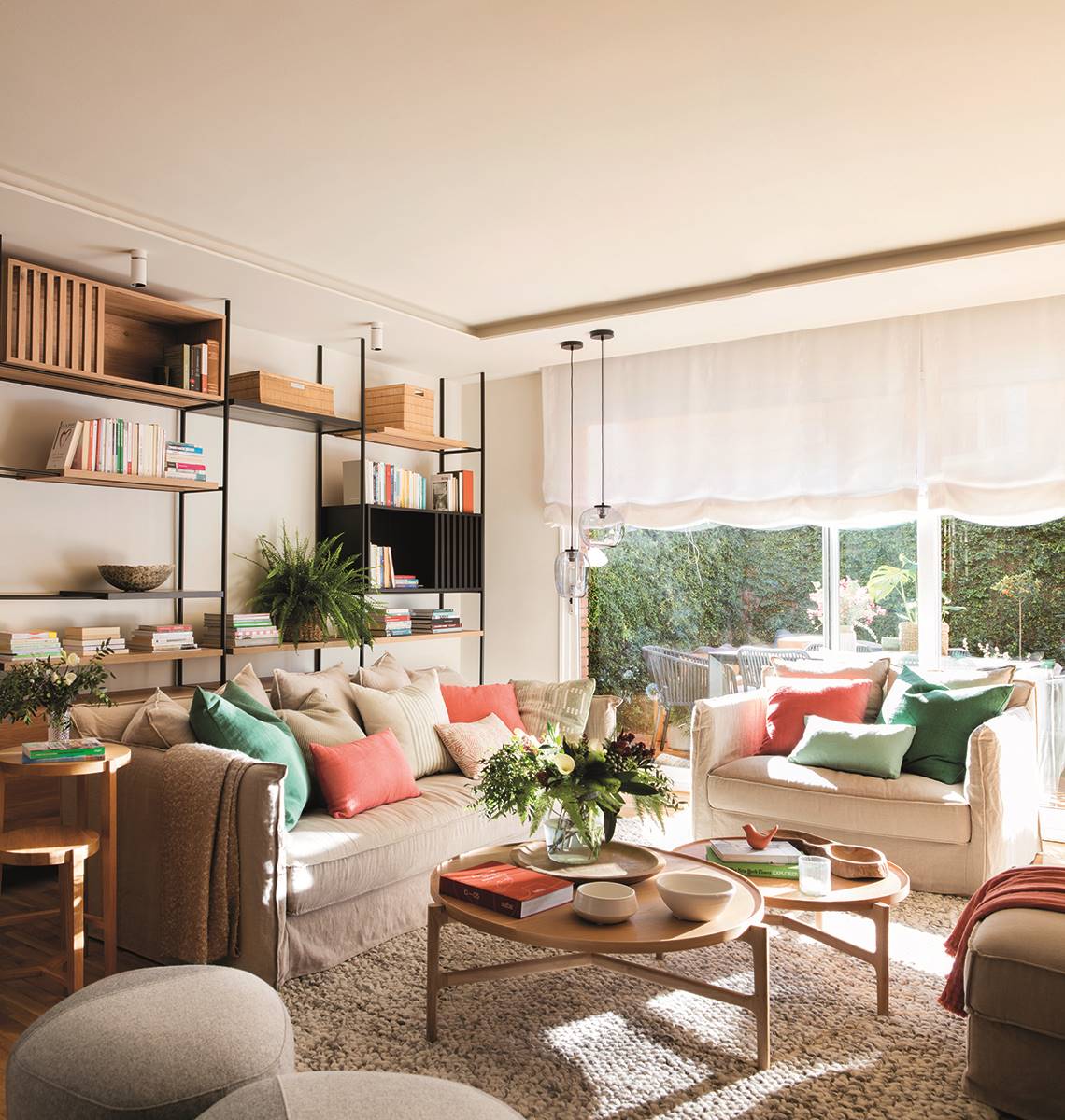 Un salón en tonos neutros con cojines de colores veerdes y rojos.