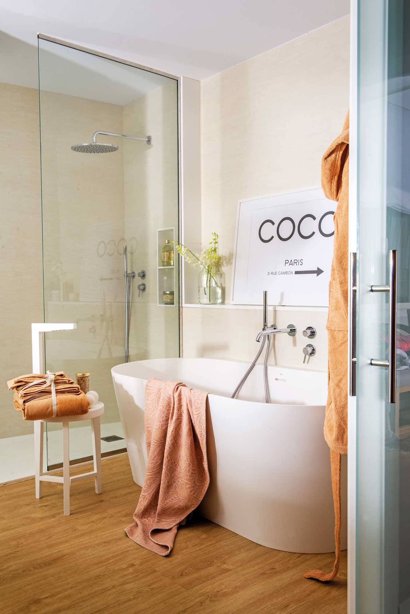 Baño con bañera exenta y suelo de madera. 