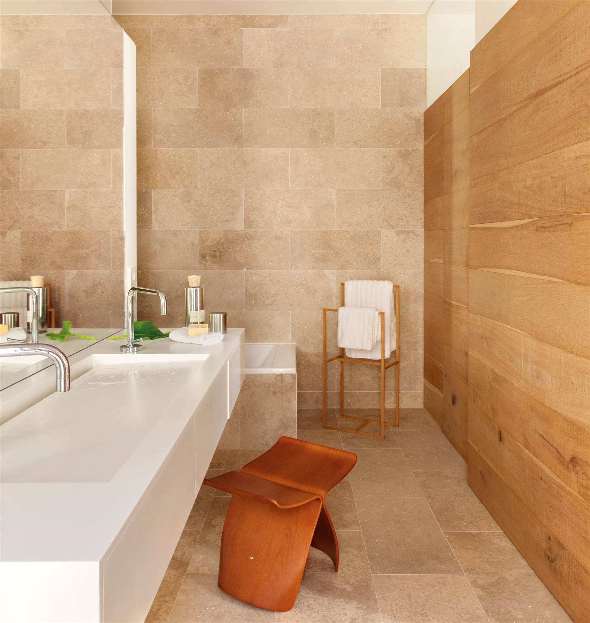 Baño moderno con lavamanos integrado en el mueble y pared de madera. 