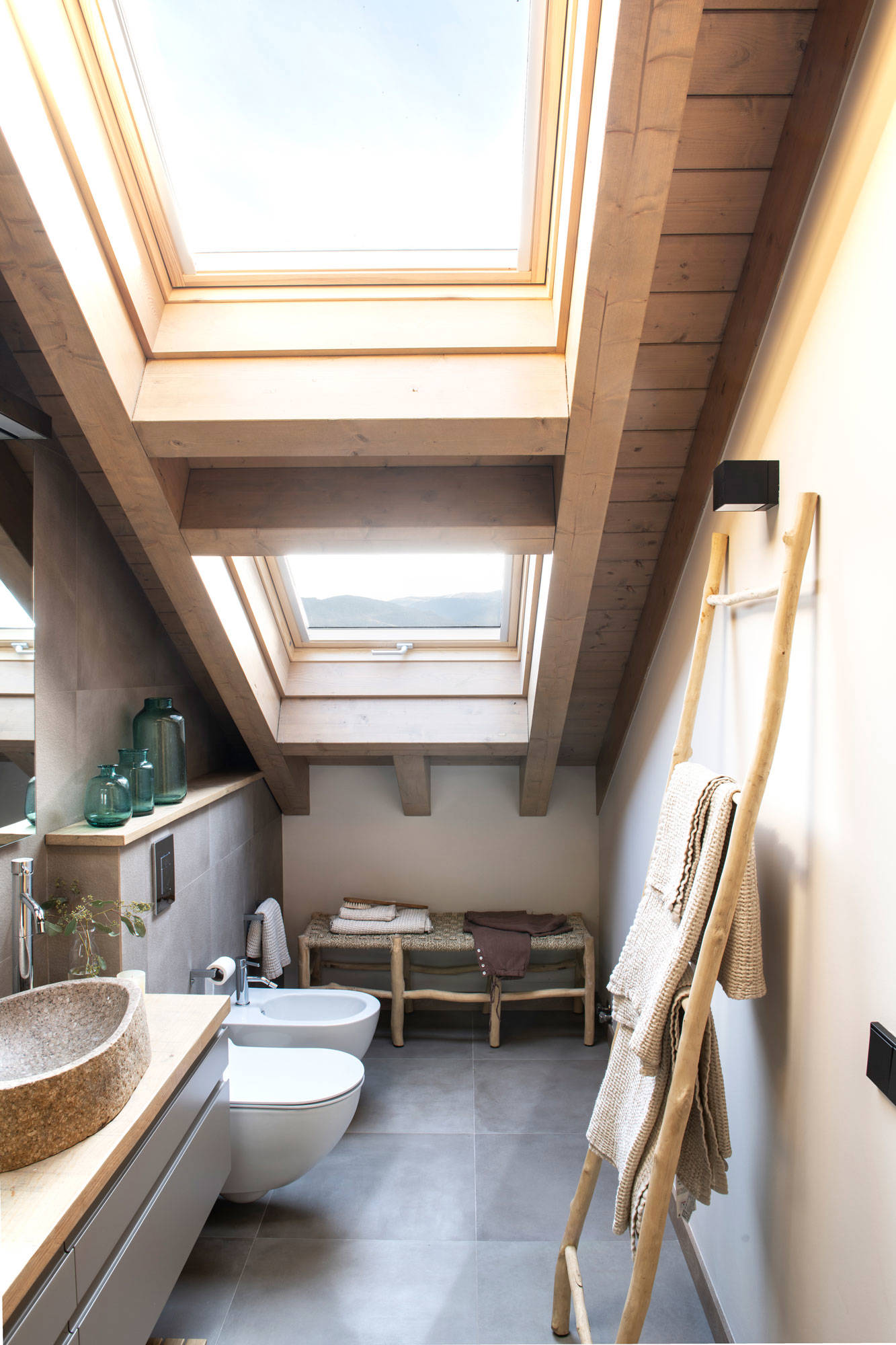 Baño con techo inclinado y estantería de obra sobre el inodoro.