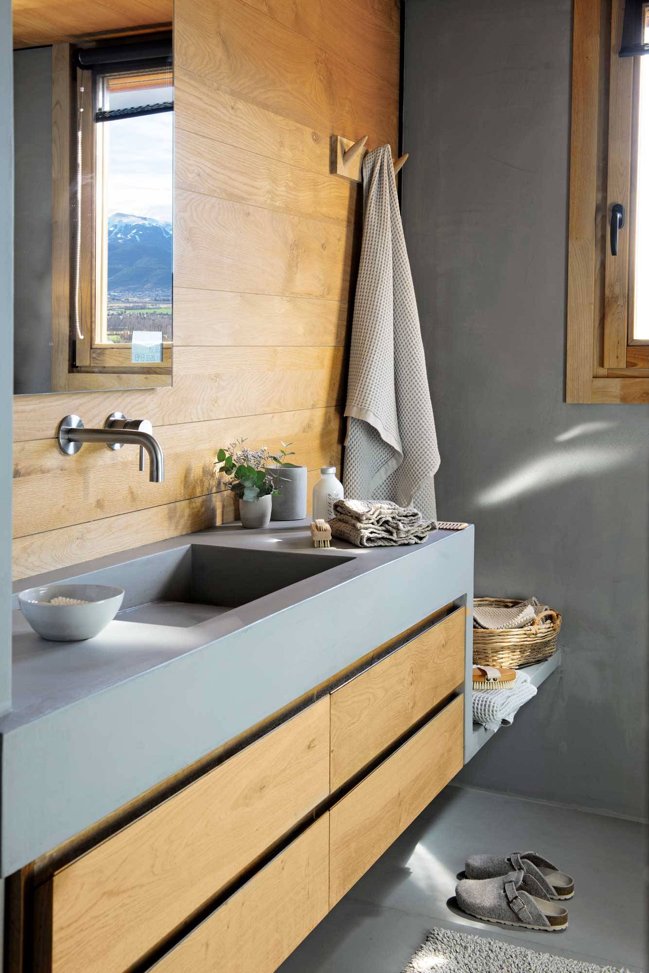 Baño moderno con encimera en microcemento gris y cajones de madera. 