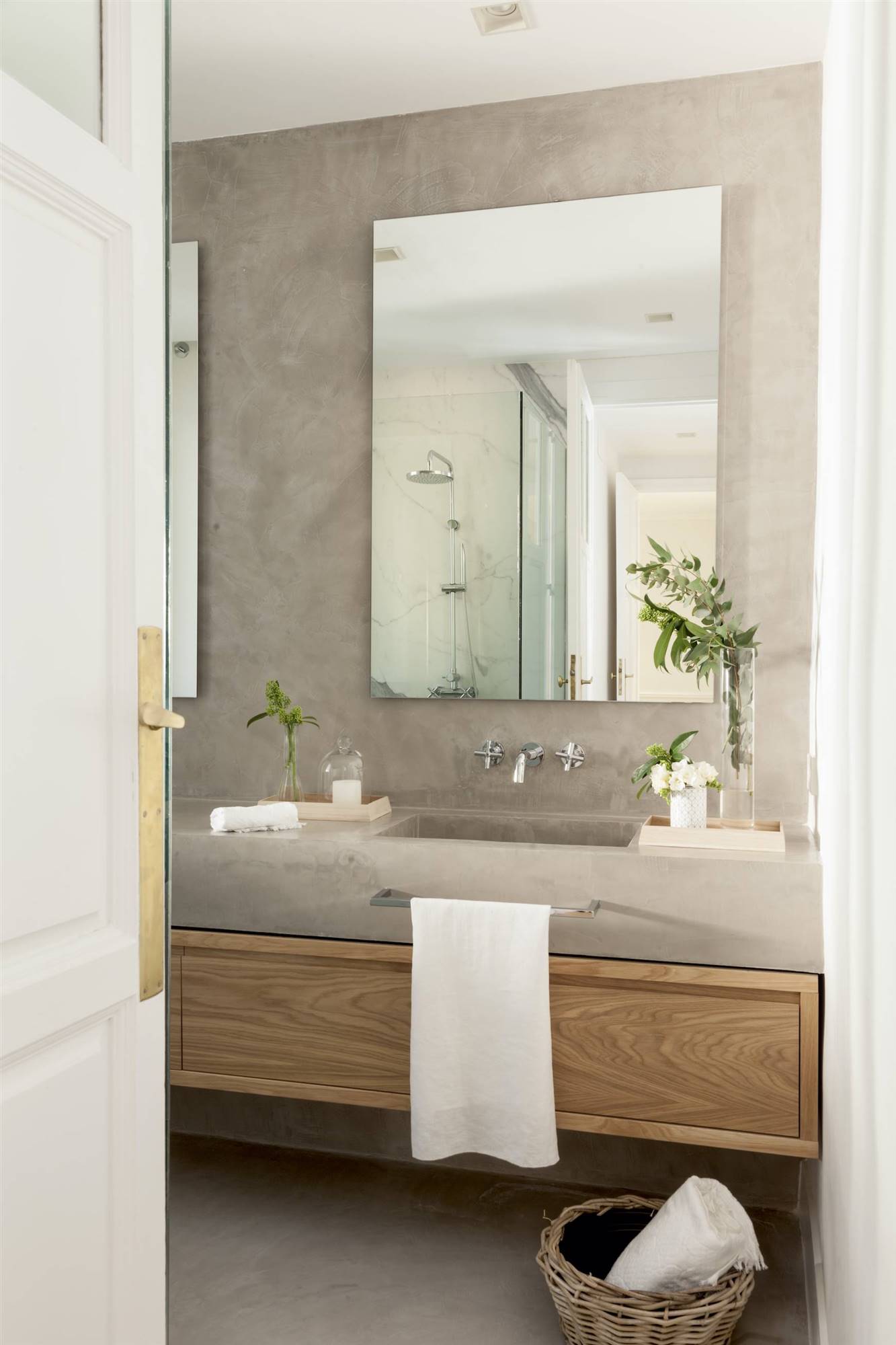 Baño revestido con microcemento y mueble de madera. 