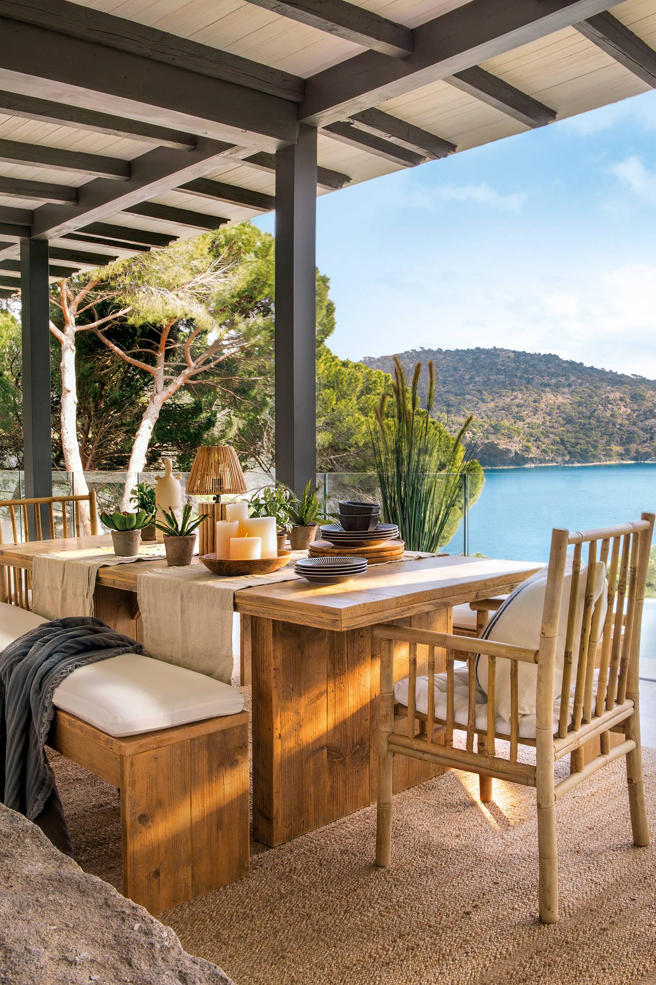 Terraza cubierta con comedor con mesa y bancos de madera. 