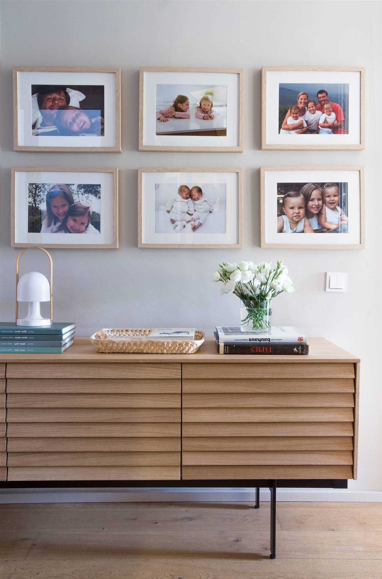 Recbidor con aparador de madera moderno y composición de fotos