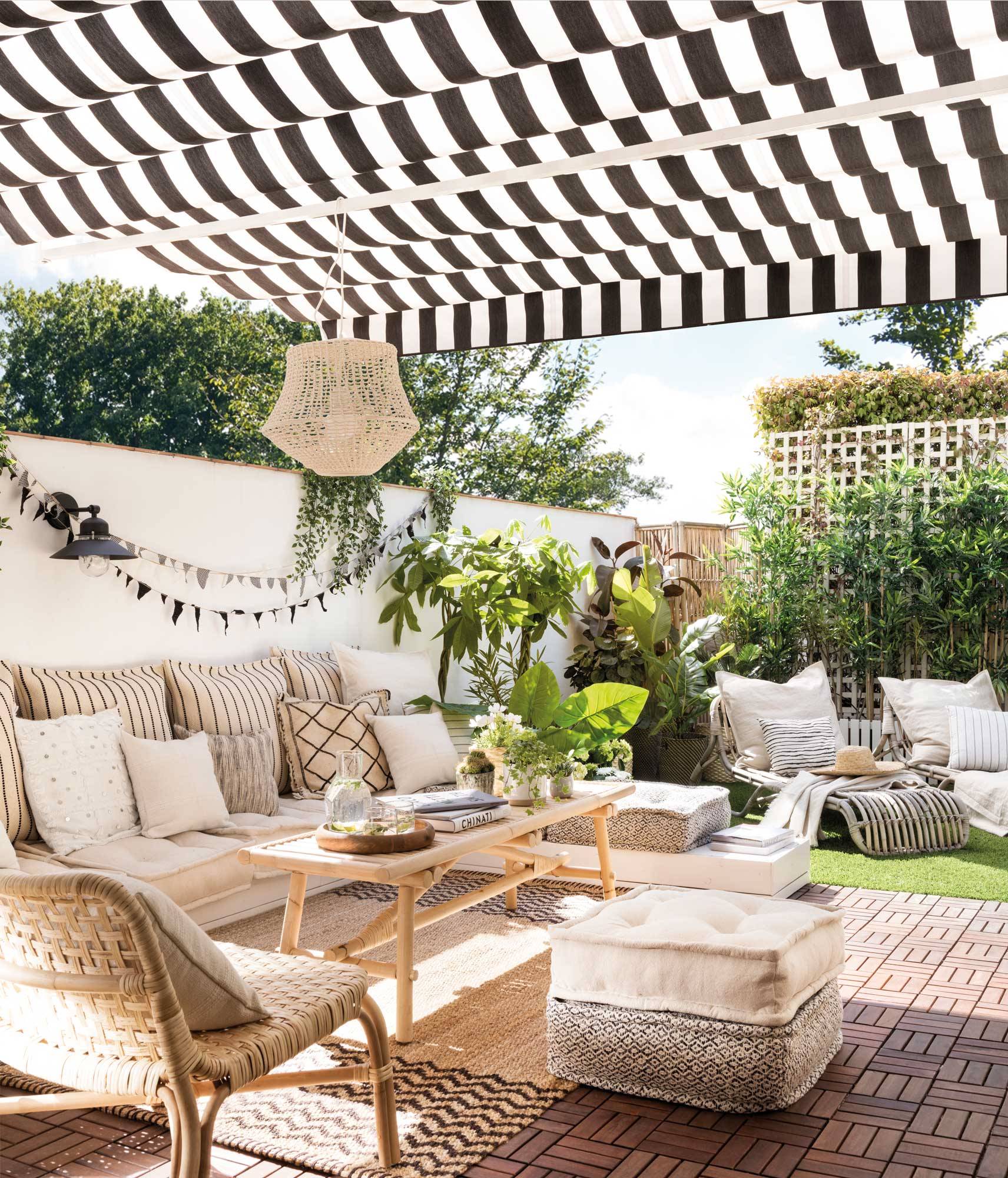 Terraza con toldo de rayas y muebles de madera y fibras naturales. 
