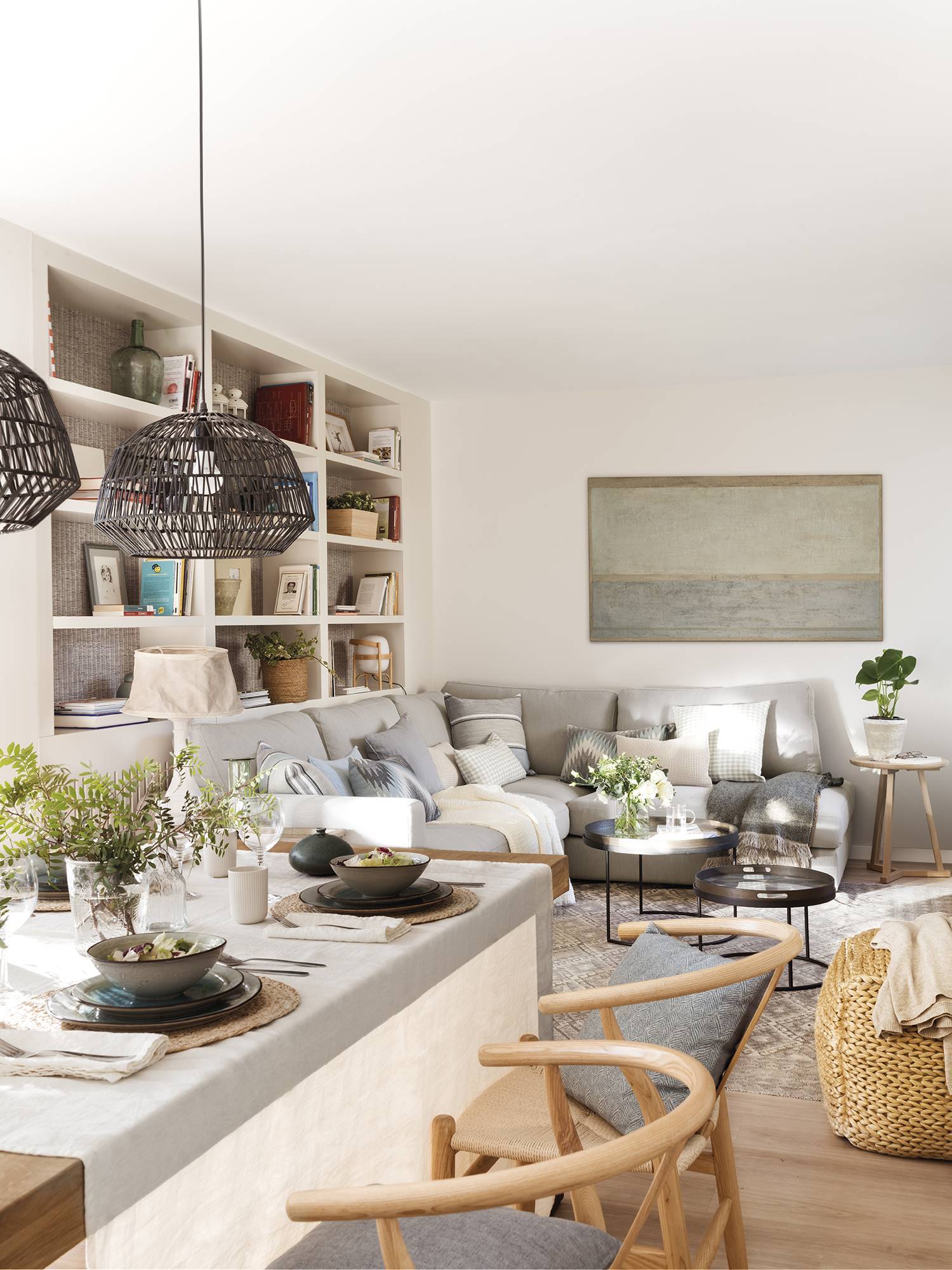 Salón pequeño abierto al comedor con sofa rinconero de color gris. 