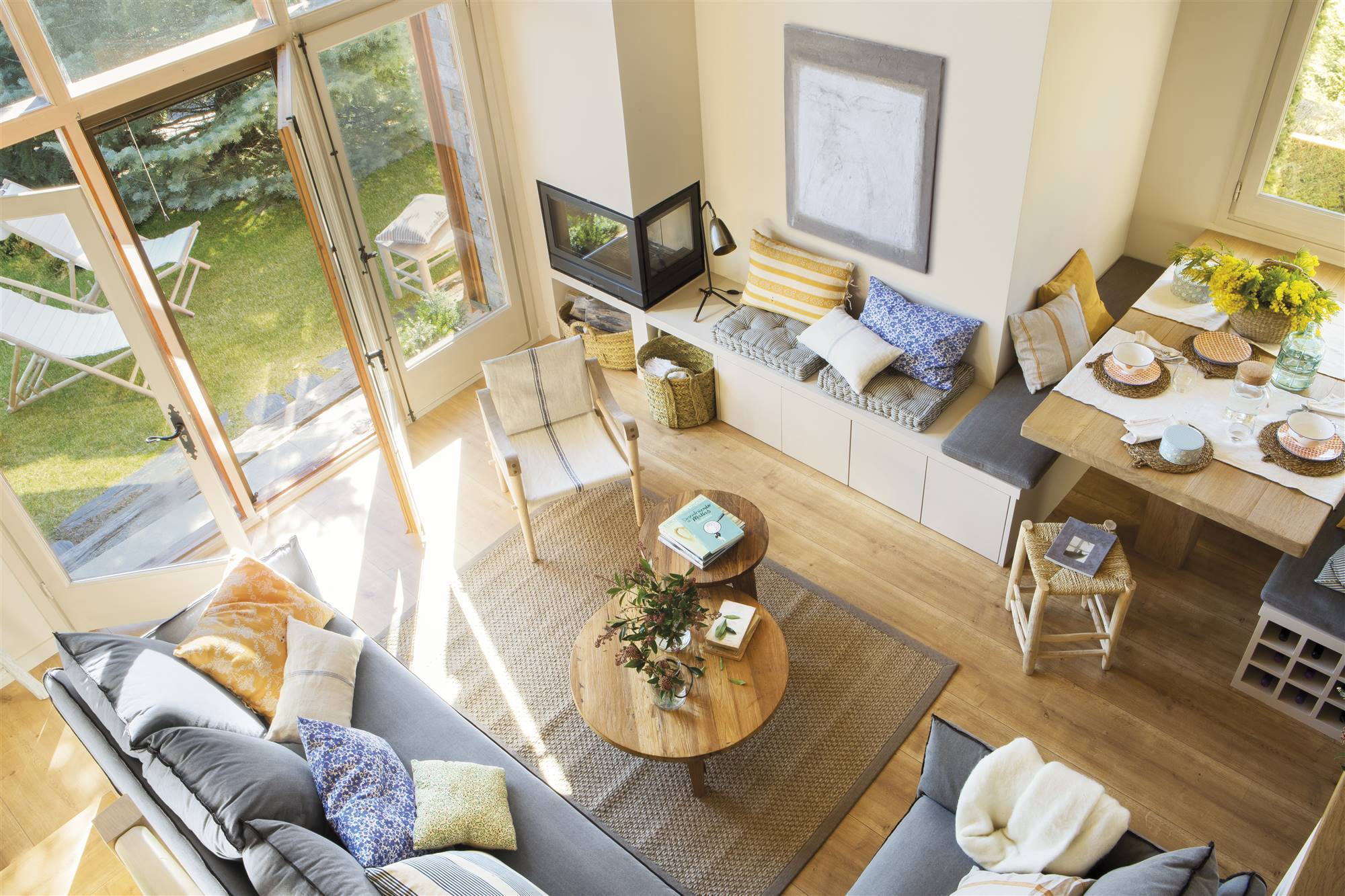 Salón con sofá esquinero con dos mesas nido de madera, banco de obra y comedor. 