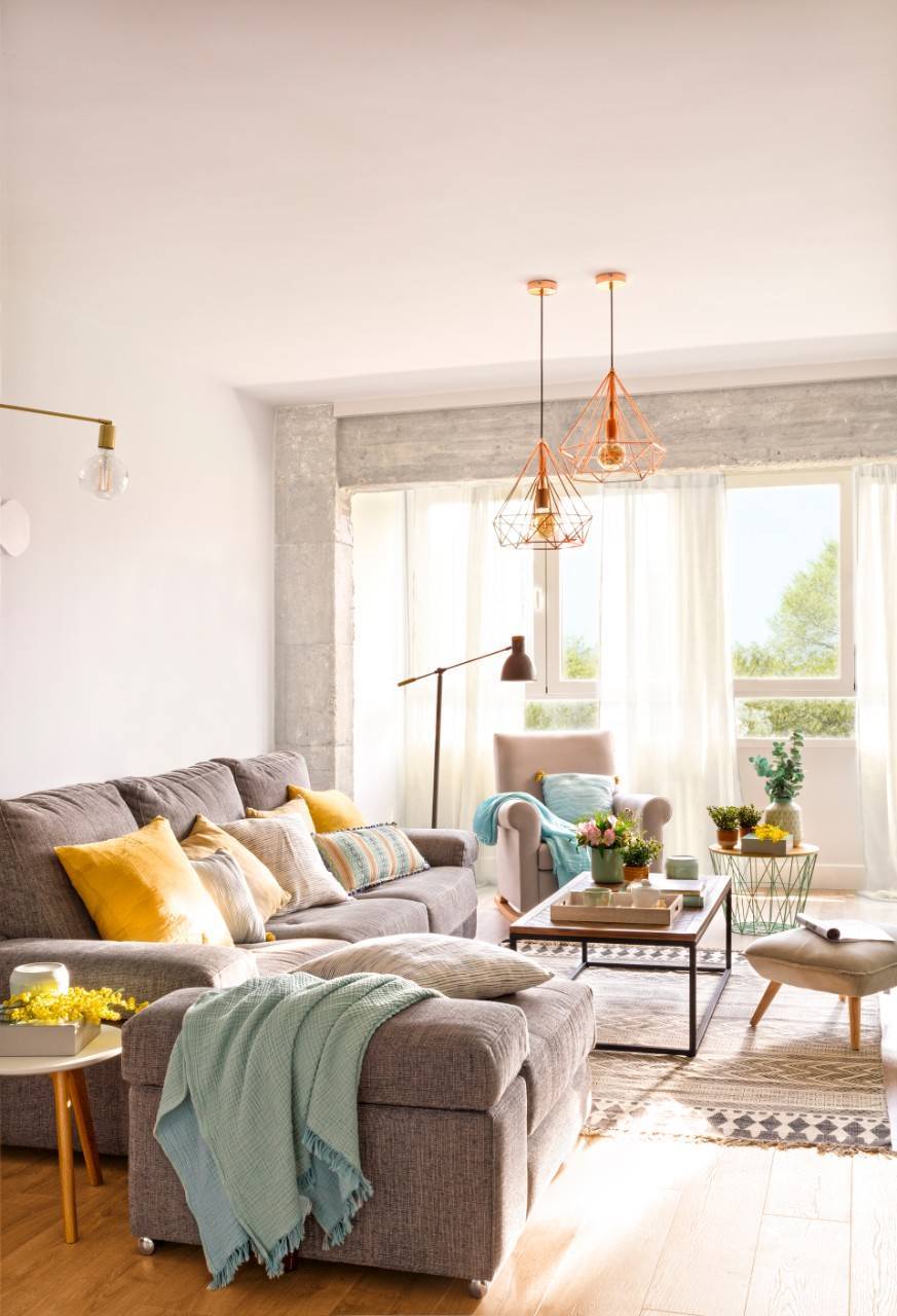 Salón con sofás y puff de color gris y mesa de centro de madera. 