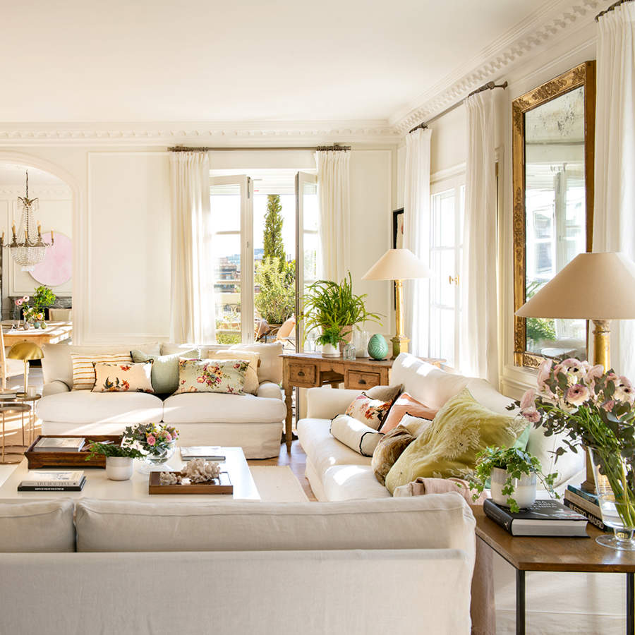 Salón elegante con sofás blancos, chimenea de mármol y estantería a medida