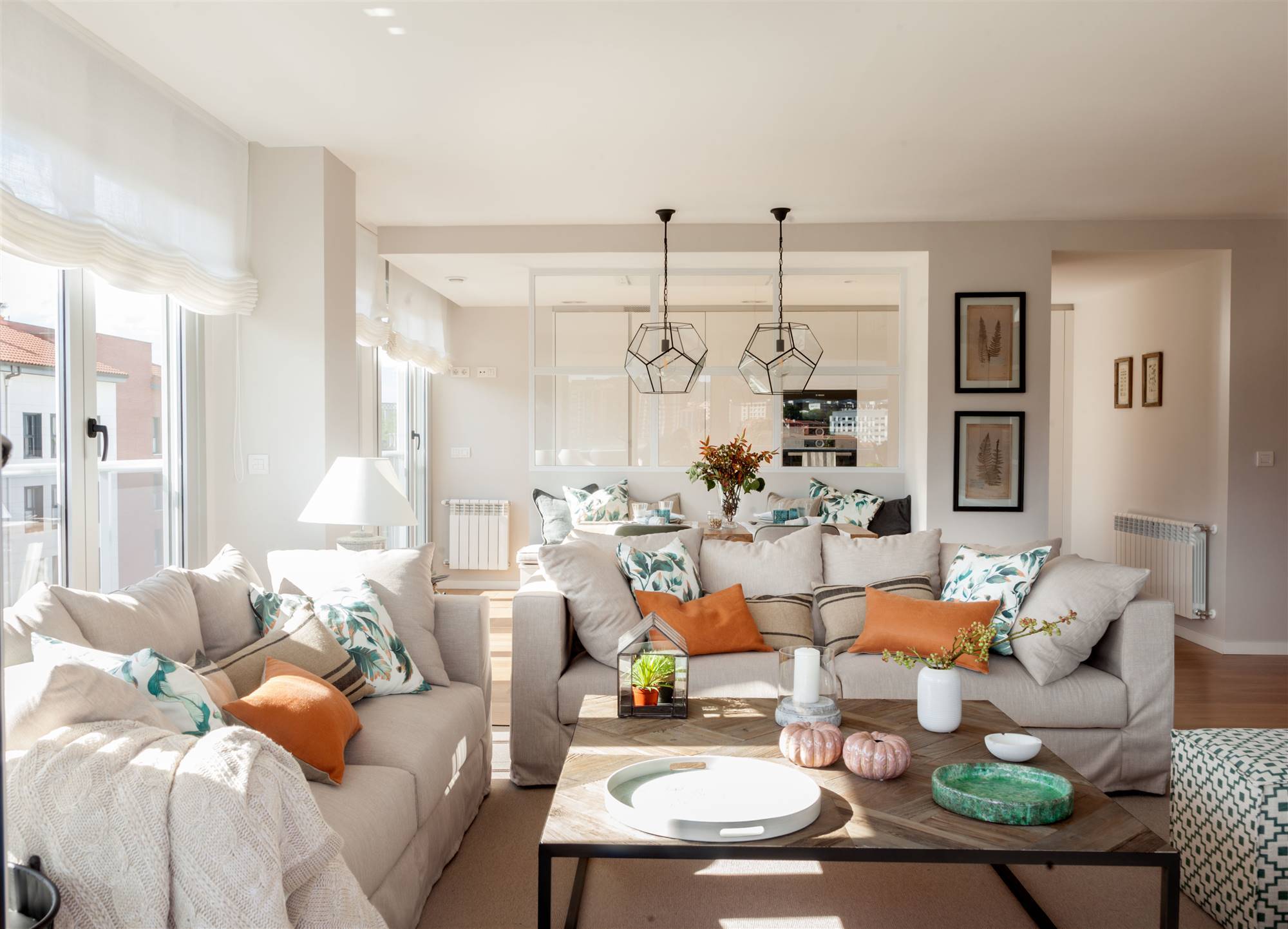 Salón moderno con sofás grises, cojines de colores y mesa de centro de madera y hierro. 