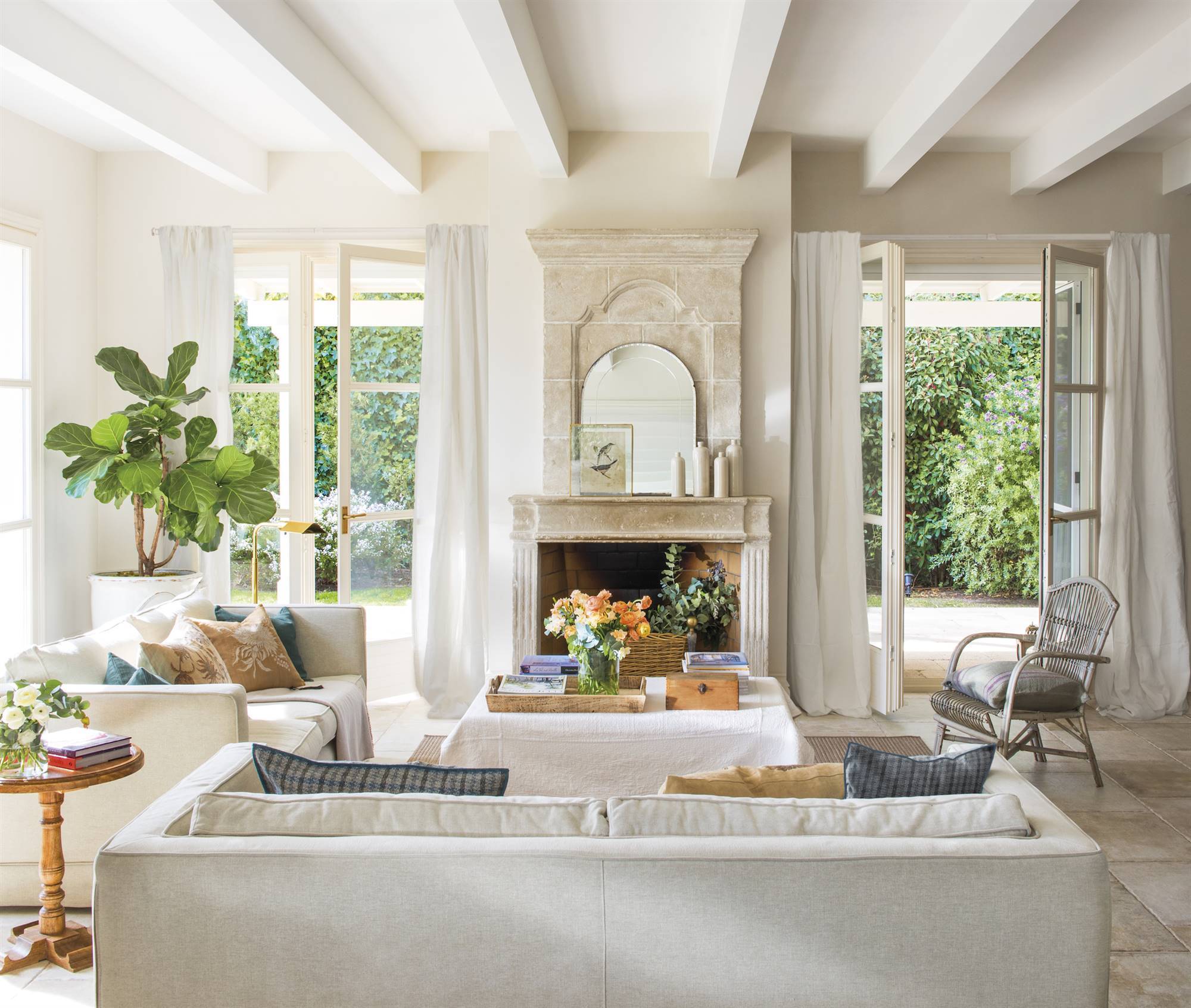 Salón decorado en blanco con chimenea de piedra. 