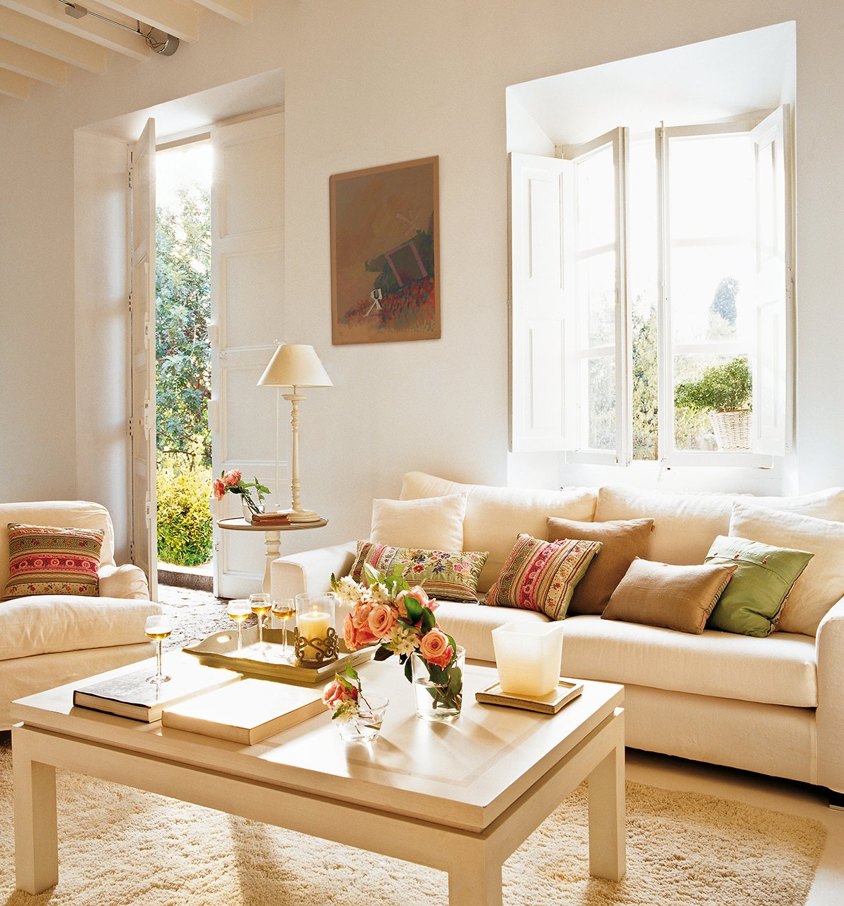 Salón pequeño con sofás y mesa de centro blancos.
