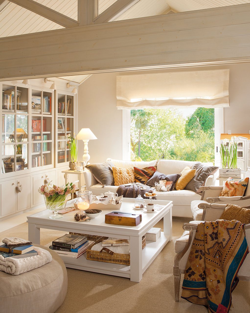 Salón con techos abuhardillados y muebles blancos. 