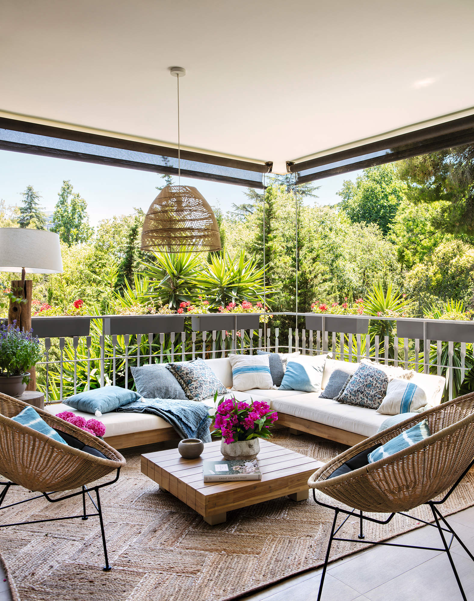 Terraza con chill out en forma de L, cojines azules y fibras naturales.