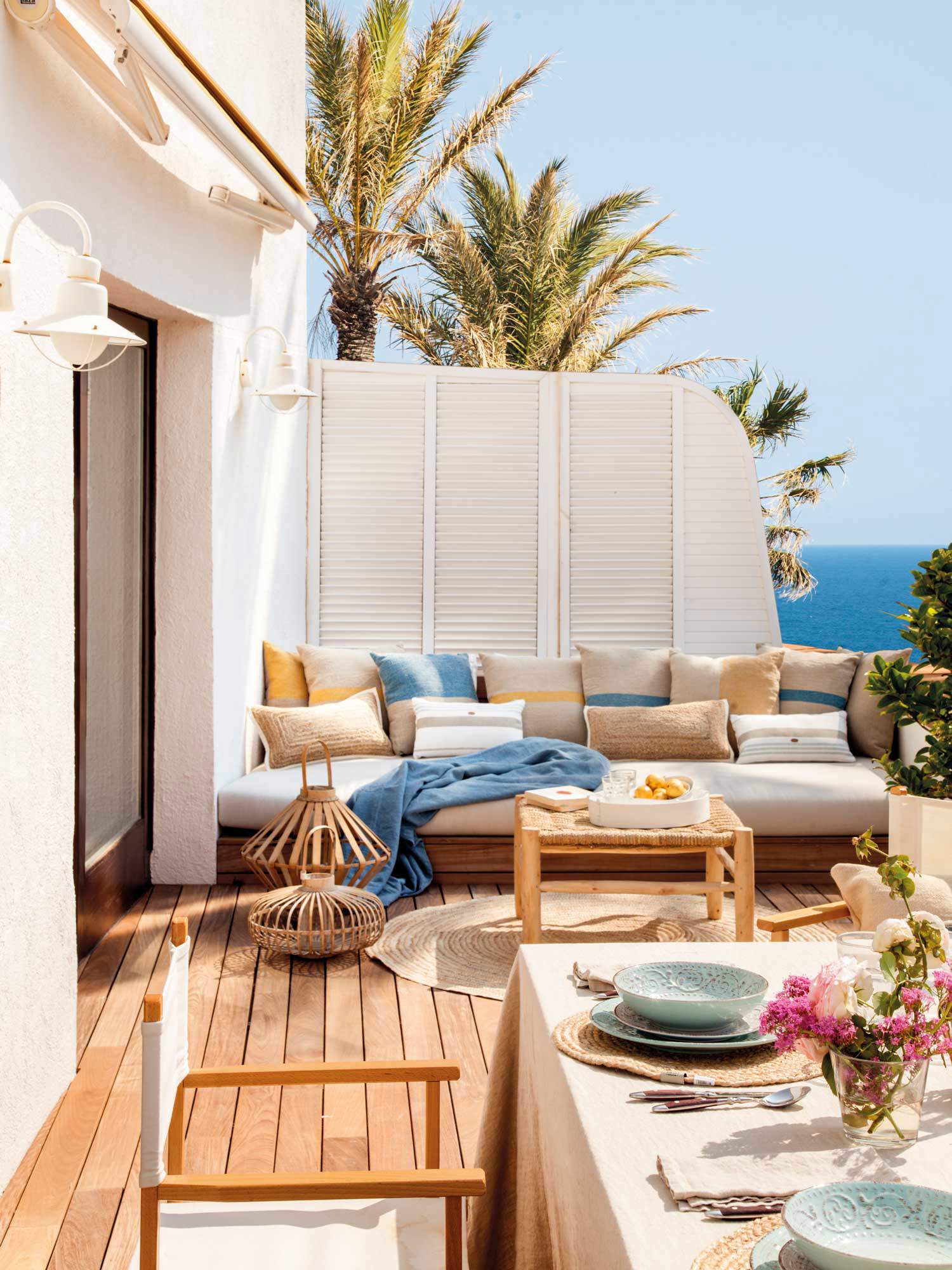 Terraza con sofá blanco y cojines en tonos azules y amarillos.