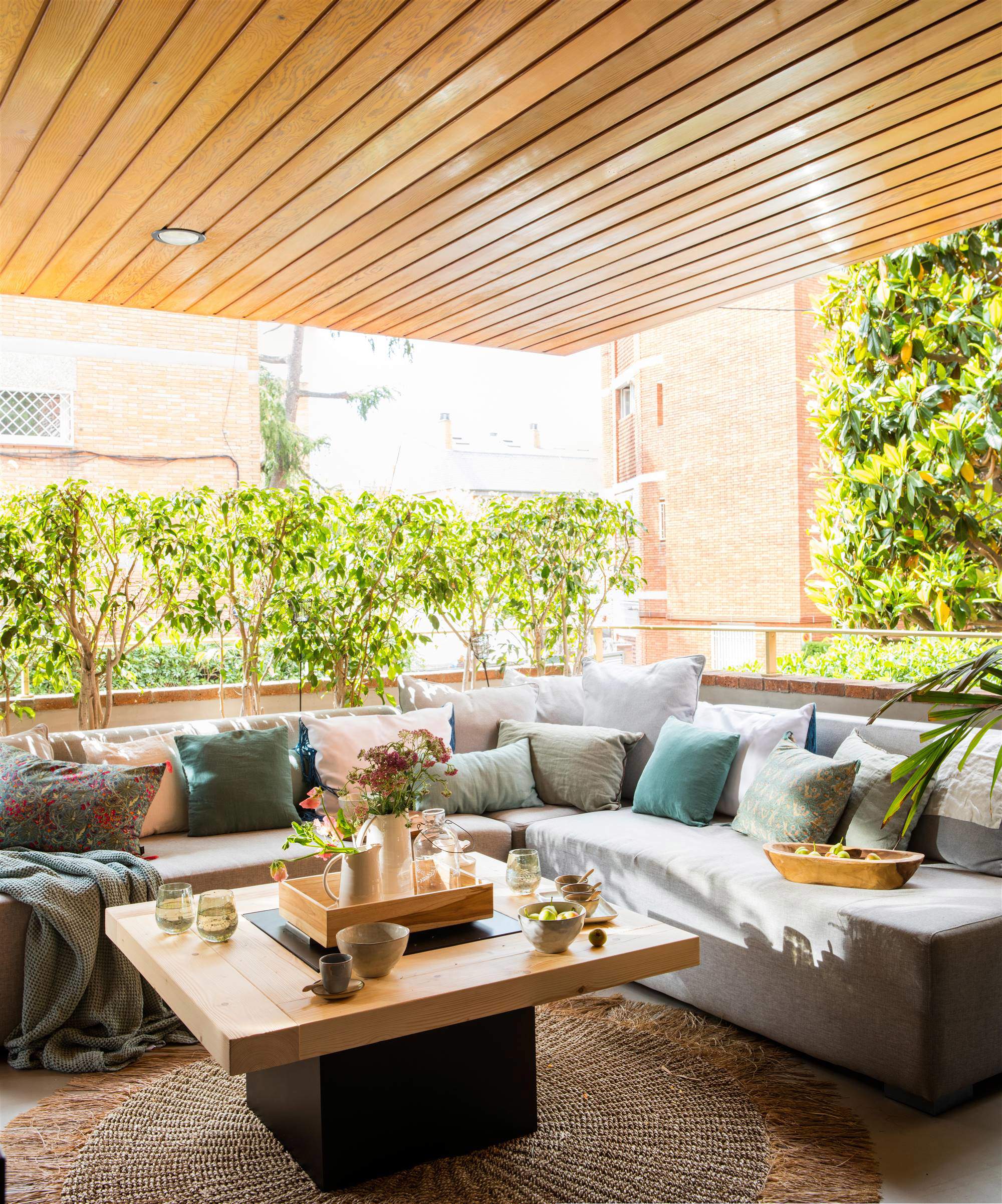 Terraza con sofá rinconero y mesa de centro, diseño de Cado Interiors.